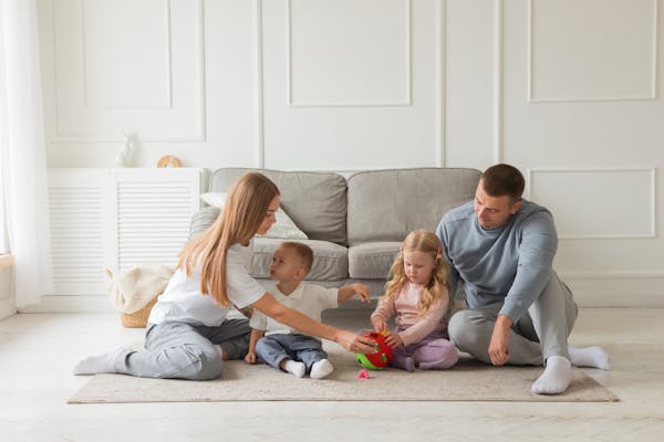 Family bonding time on the carpet in a cozy living room setting.
